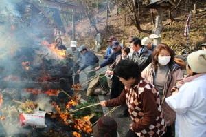 火の周りにあるまり餅をやく人たちの写真