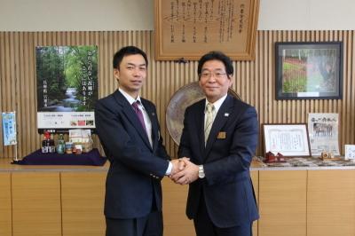 市役所の部屋で撮影された青年海外協力隊員の名畑晋也さんと市長の写真