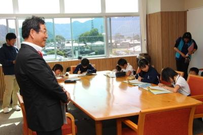 波賀小ふるさと宍粟探検隊が熱心に筆を執っているのを見守る市長の写真