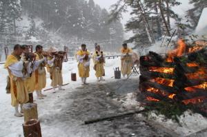 板馬見山大とんどで燃え盛る火の周りで祈祷されている様子の写真