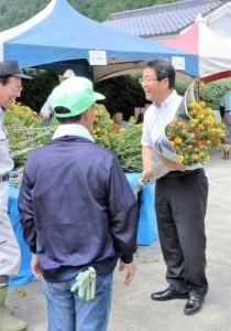 べにばなの花束をもつ市長と祭り参加者が笑顔で会話をしている写真