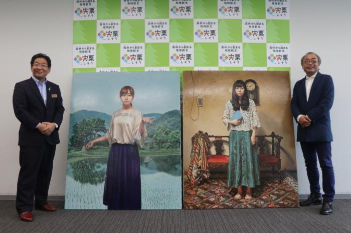 2枚の絵画を横に記念撮影する市長と志水和司様の写真