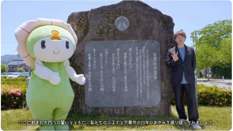 宍粟市市民憲章が刻まれた石の左側に宍粟市のマスコットキャラクターしーたんが、右側にしそうチャンネルのレポーターが立ち、宍粟市の20年のあゆみを振り返ってみましょうのテロップが下部に表記された写真