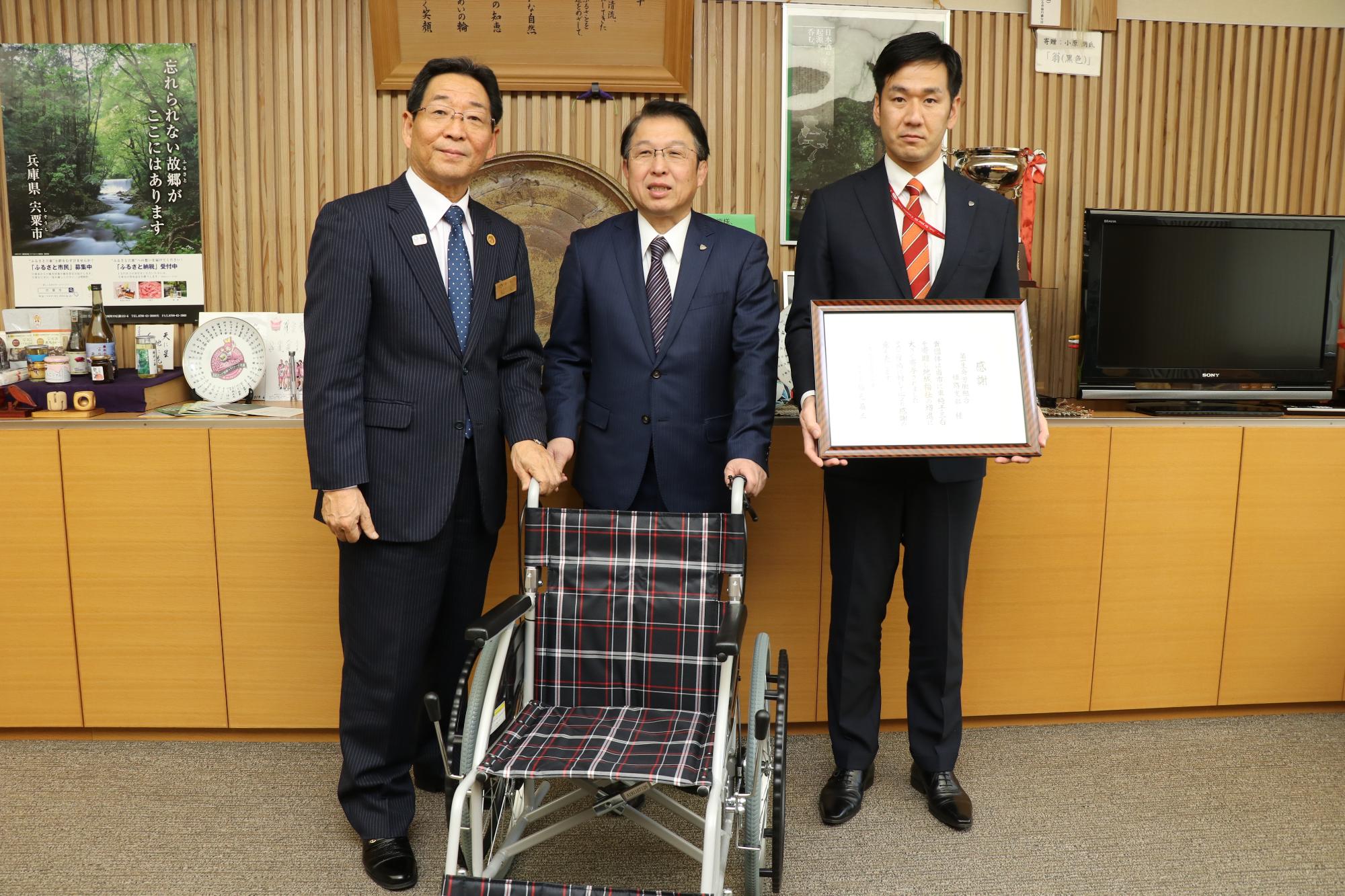 感謝状を手にした第一生命労働組合姫路支部さんが車椅子と一緒に市長と並んでいる写真