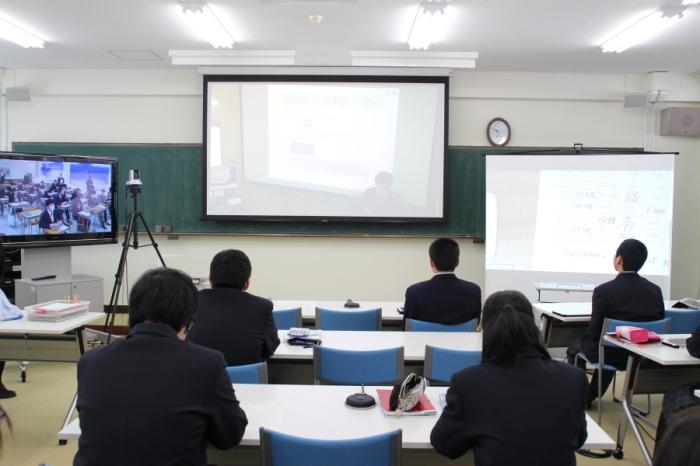 教室の3つのスクリーンにホワイトボードと通信先の教室で授業を受けている生徒とホワイトボードの別の角度の映像が移され遠隔授業を受けている高校生の写真