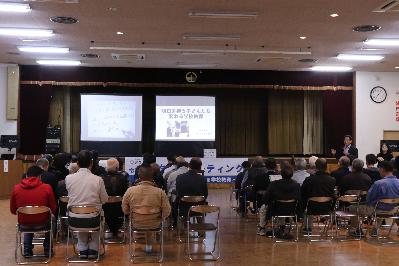 センター波賀タウンミーティングでステージのスクリーンに映し出された画像を見ている参加者らの写真