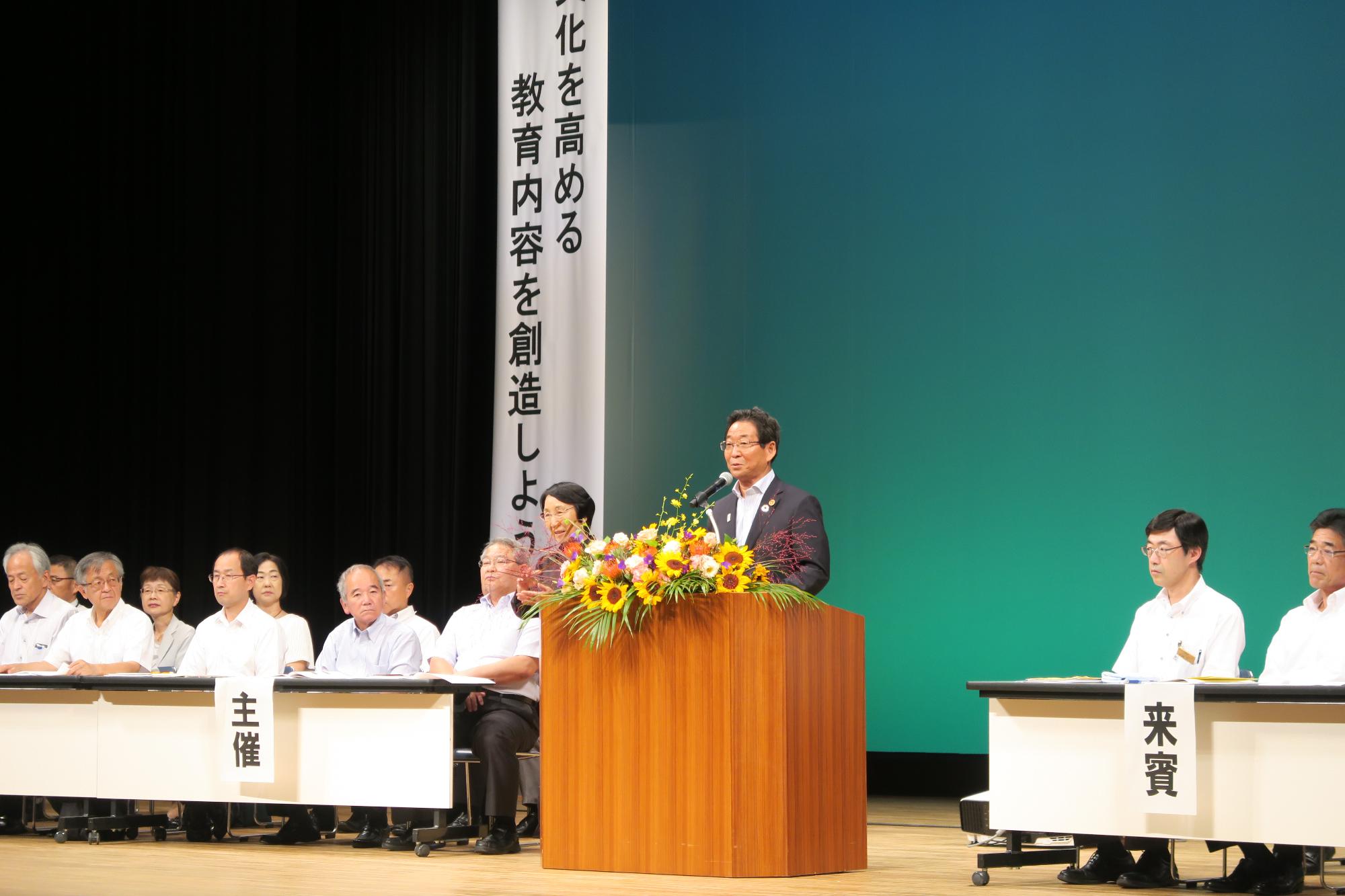 8月18日の兵庫県人権教育大会西播磨地区大会のステージの演題で祝辞を述べる福元市長の写真