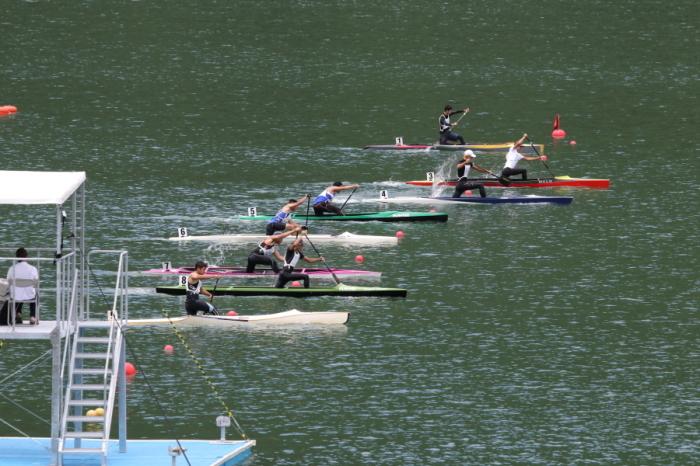 競技者が勢いよくパドルを漕いでいるカヌーのレーススタート直後の写真