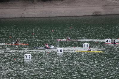 5台のカヌーが湖中央でレースをしている写真