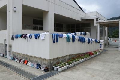 着衣水泳の授業のあと濡れた衣服と靴を干している校舎一角の写真