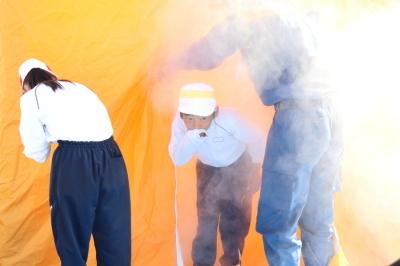 オレンジ色のテントのなかで煙を発生させ、火災時の煙を体験する小学生たちの写真