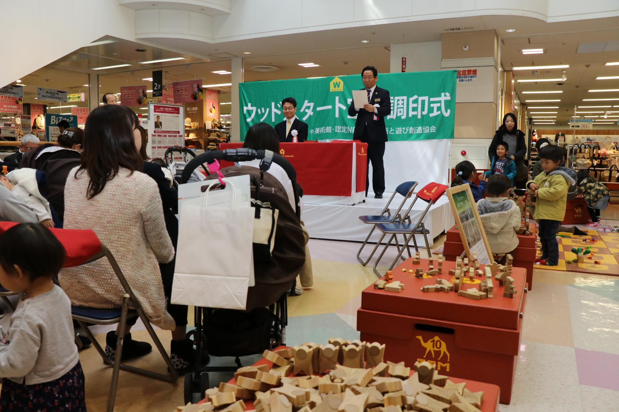 モールの吹き抜け部分に宣言調印式のため設営されたステージで市長がスピーチをしている写真