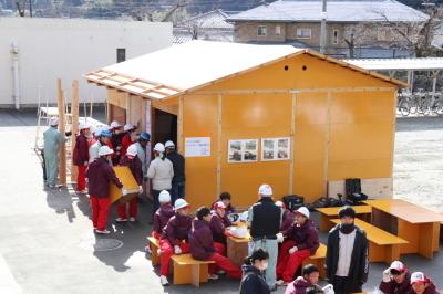設置された木造仮設住宅を見ている山崎高等学校の生徒達の写真