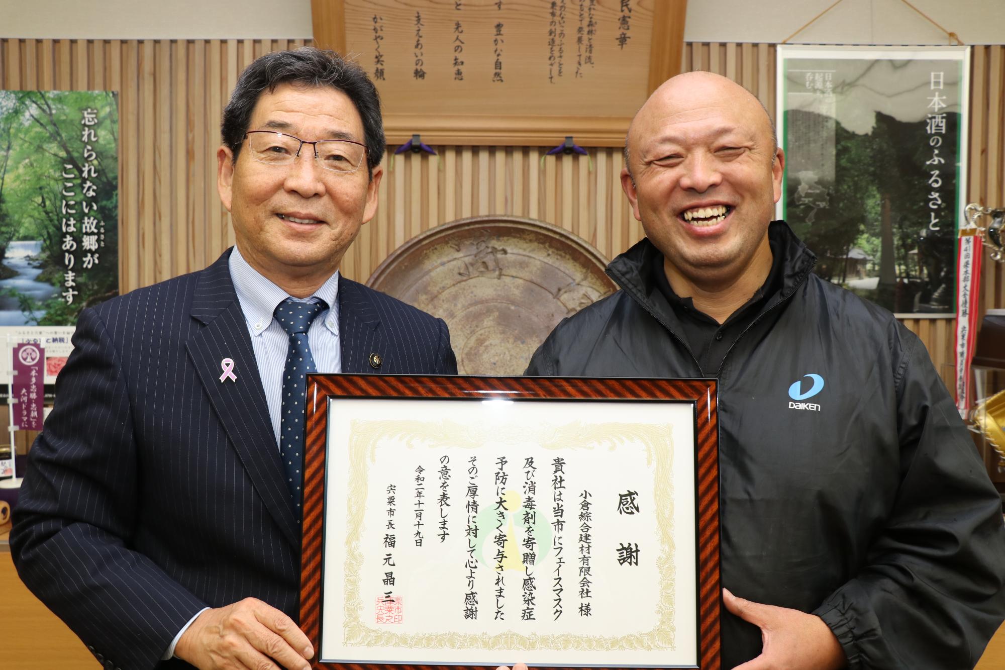 市長室にて感謝状を手に笑顔の小倉さんと福元市長の写真