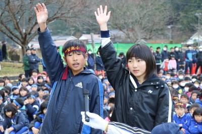 選手代表の学生の男女が右手を上げて選手宣誓をしている写真