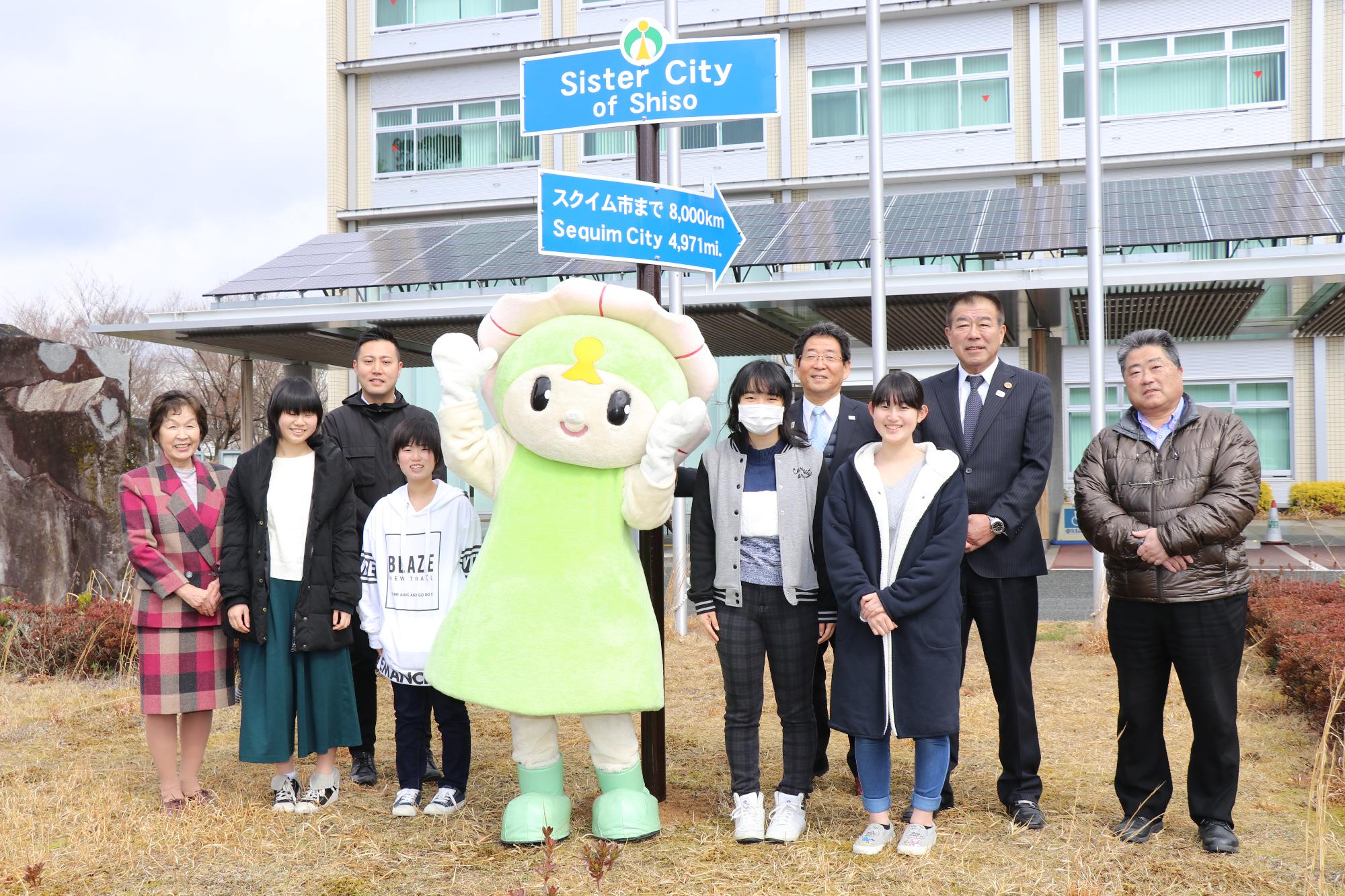 姉妹都市との友好記念標識の前で宍粟市ご当地キャラクターと関係者の記念写真
