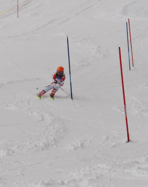 雪の積もった急斜面をスキーで滑降する選手の写真