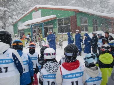 雪が降る中でスキー大会開会式をする選手達の写真