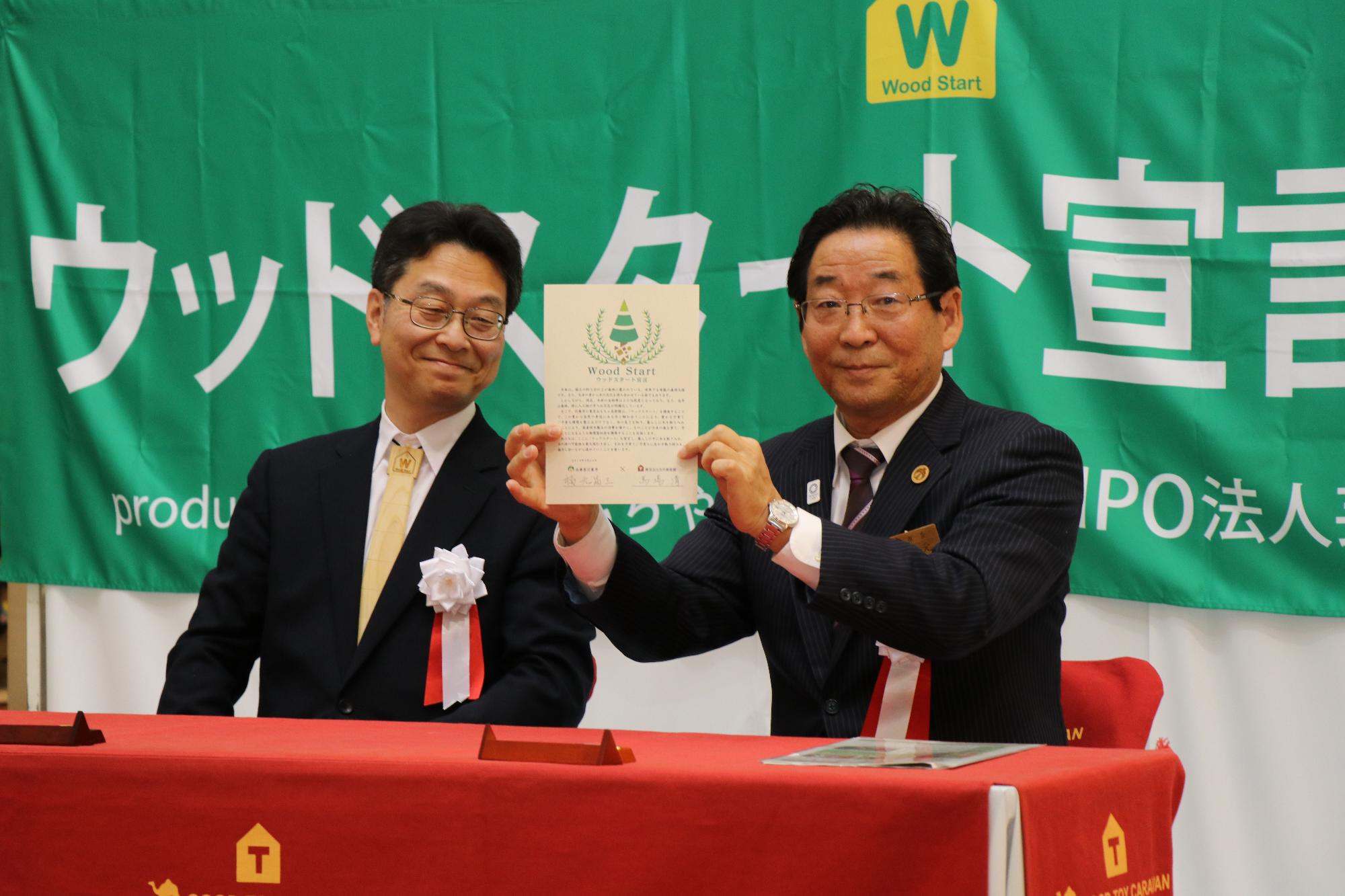 調印した宣言書をカメラに向ける市長と美術館副館長の写真