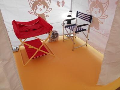 赤と黒の折りたたみ椅子と扇風機とランプが設置されたテント内観