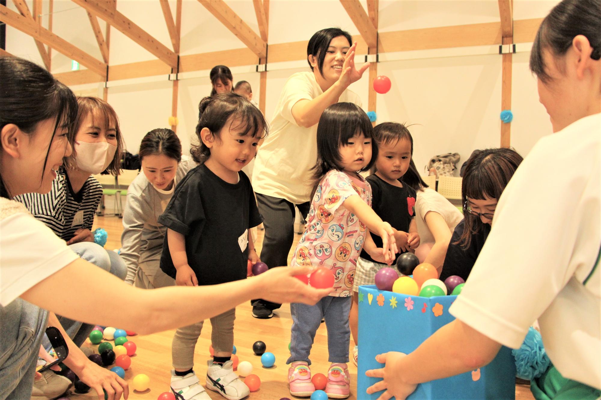 玉入れ競争に参加してカラーボールを箱に入れる親子の様子