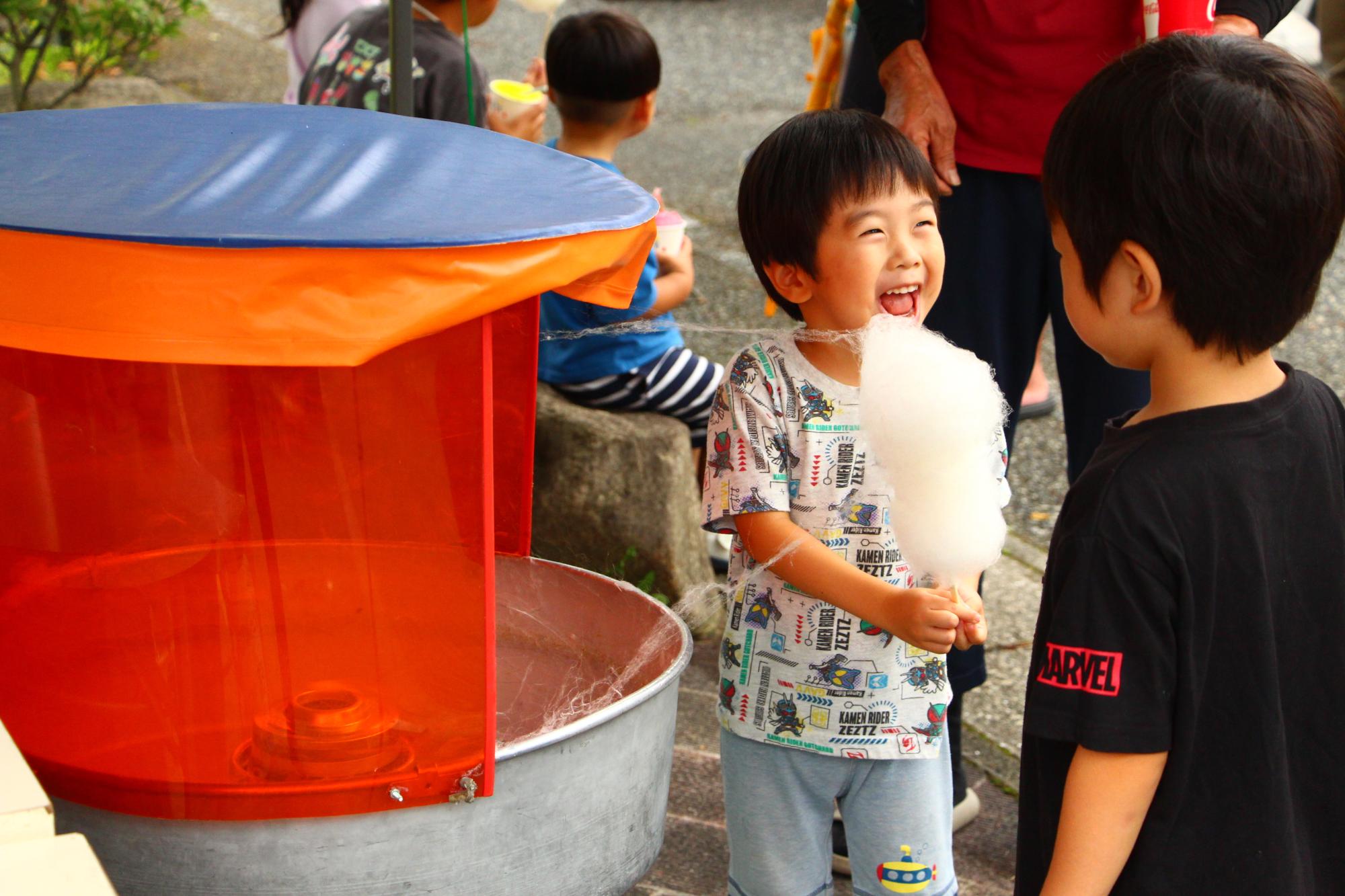 自分で作ったわたあめを満面の笑みで持つ子どもの様子