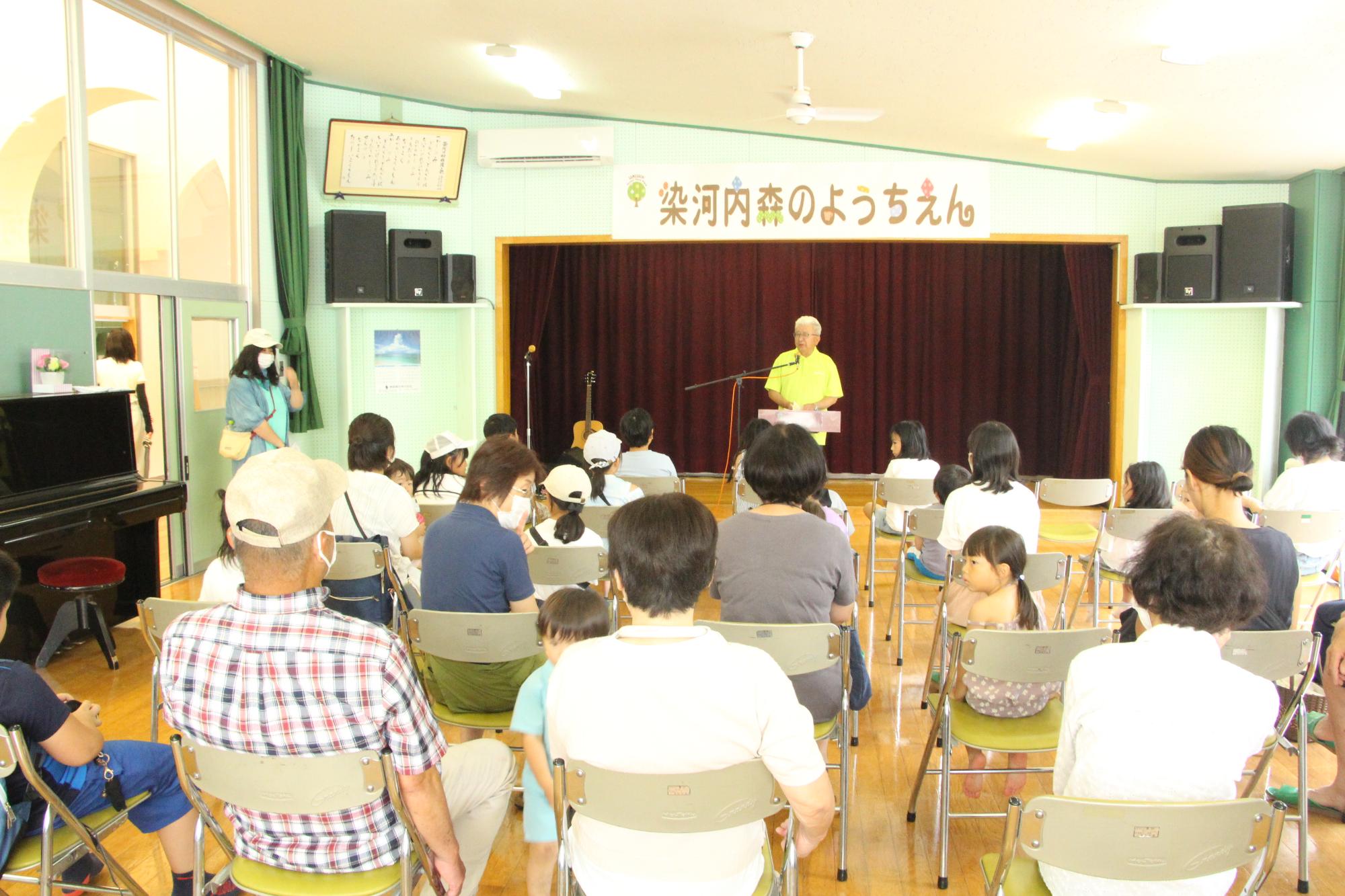 染河内森のようちえん代表の山本正幸さんが来場者を前に開会のあいさつをしている写真