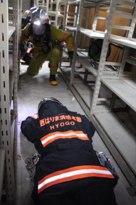 消防組合員がうつ伏せで倒れた負傷者約の隊員を、救出しようとしている写真