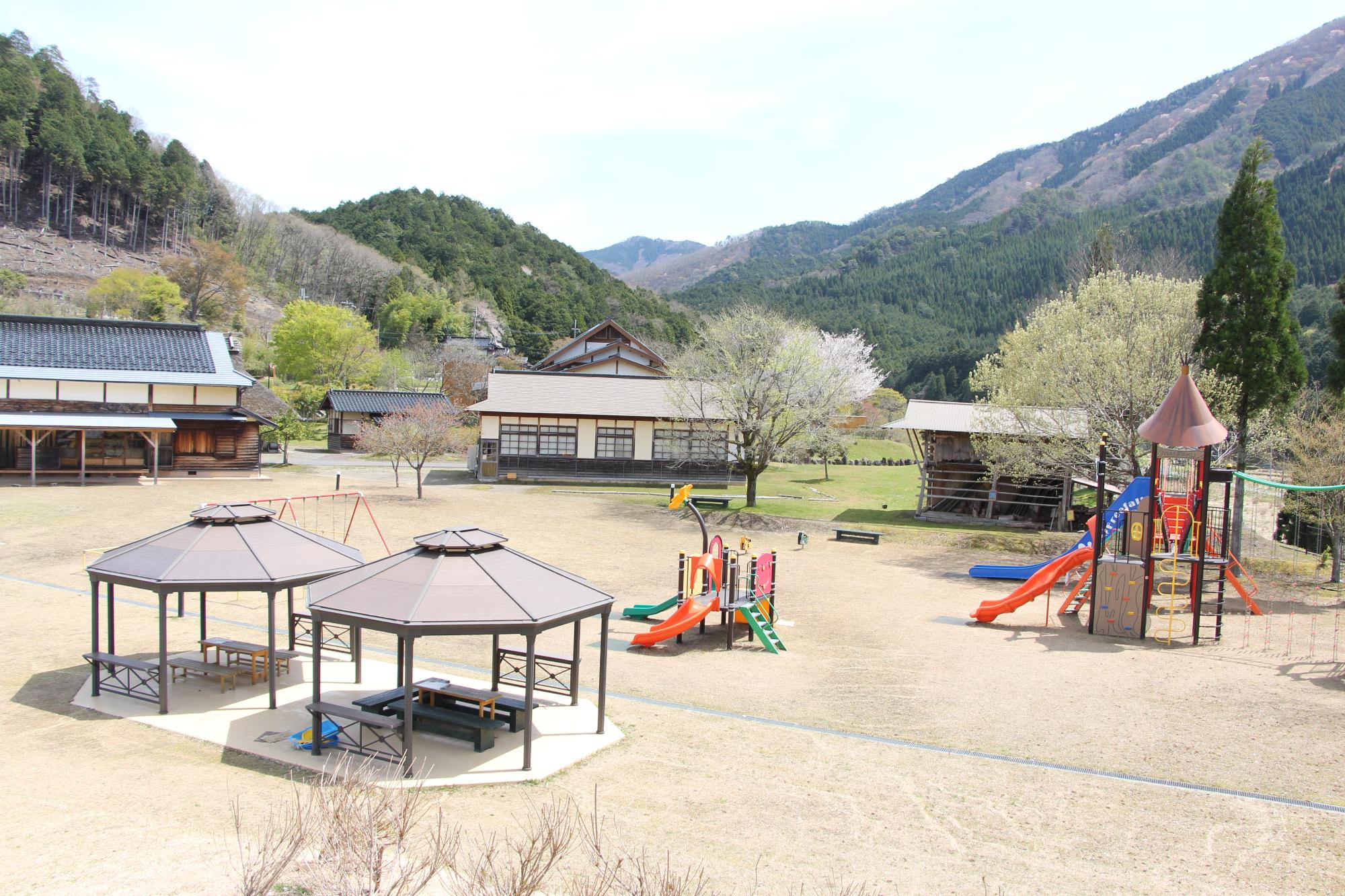 中世の住宅や東屋のほか子ども用の遊具が並ぶ家原遺跡公園の写真