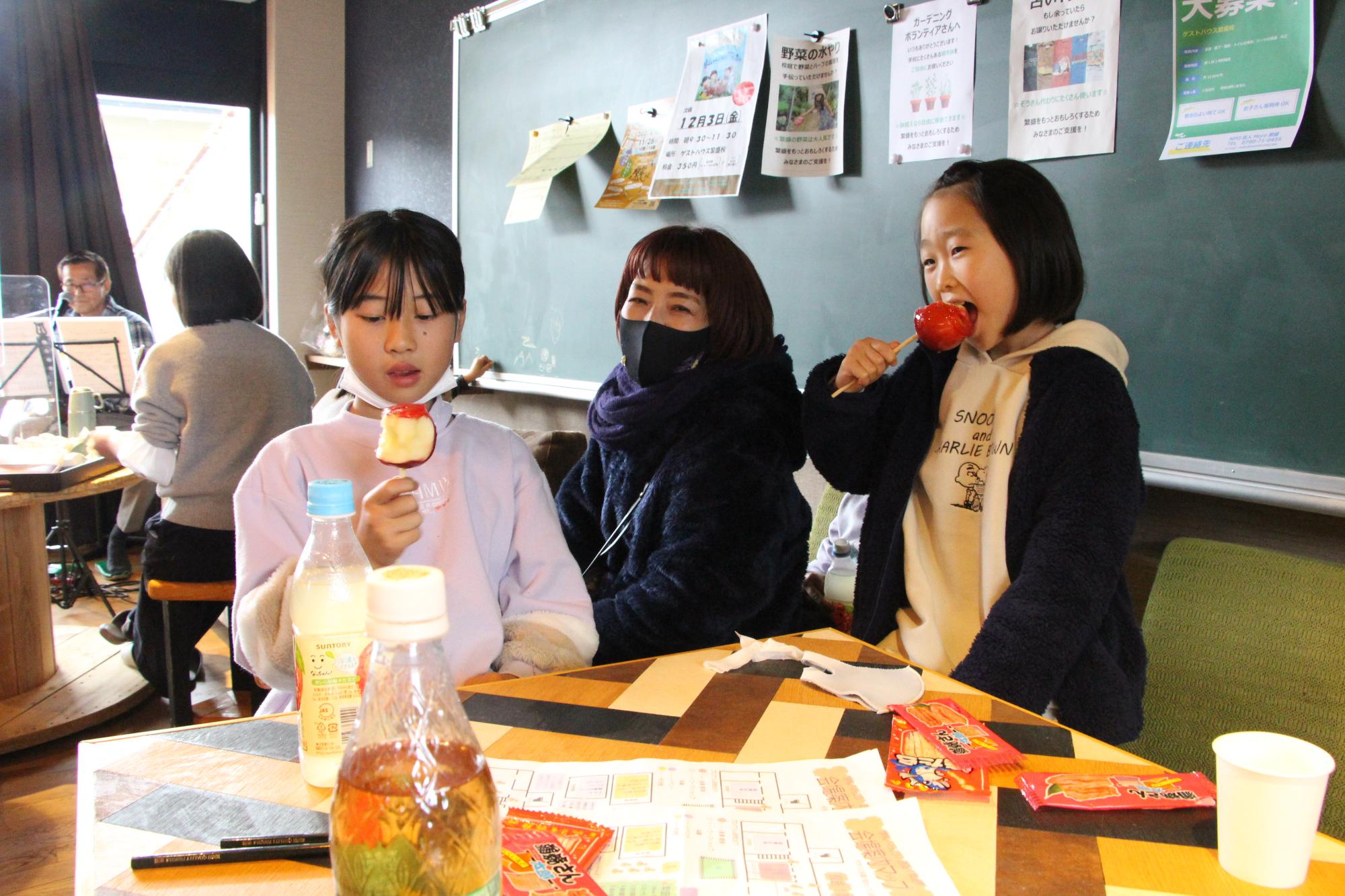 繁盛祭でりんご飴にかじりつく地元の小学生らの写真