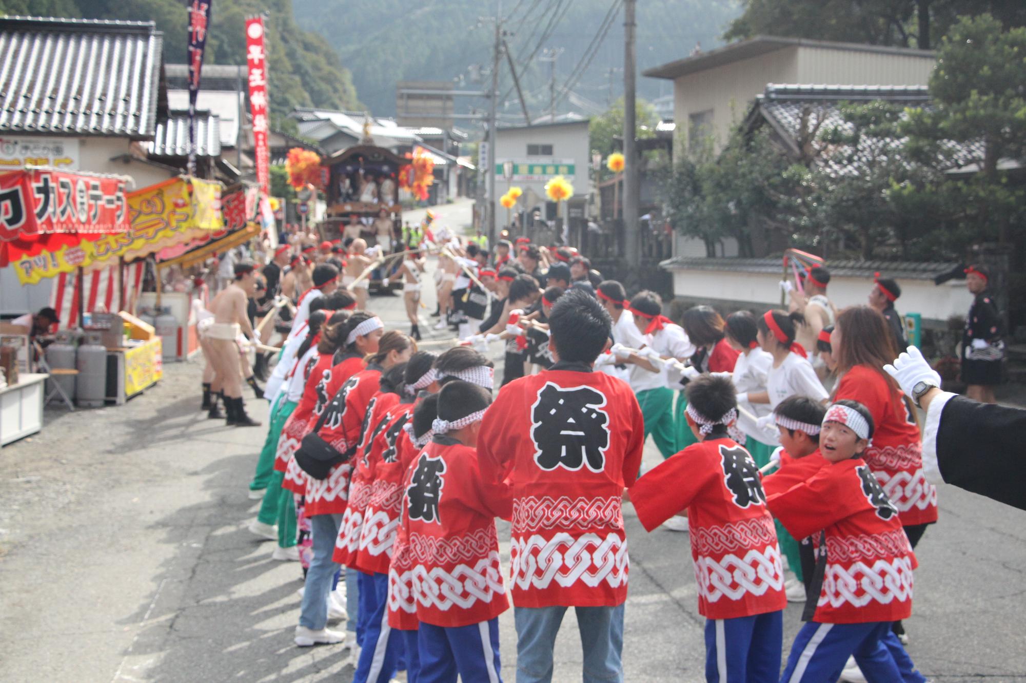 神事の後、まわし姿の成人男性や法被姿の子どもたちがた壇尻を引いている写真