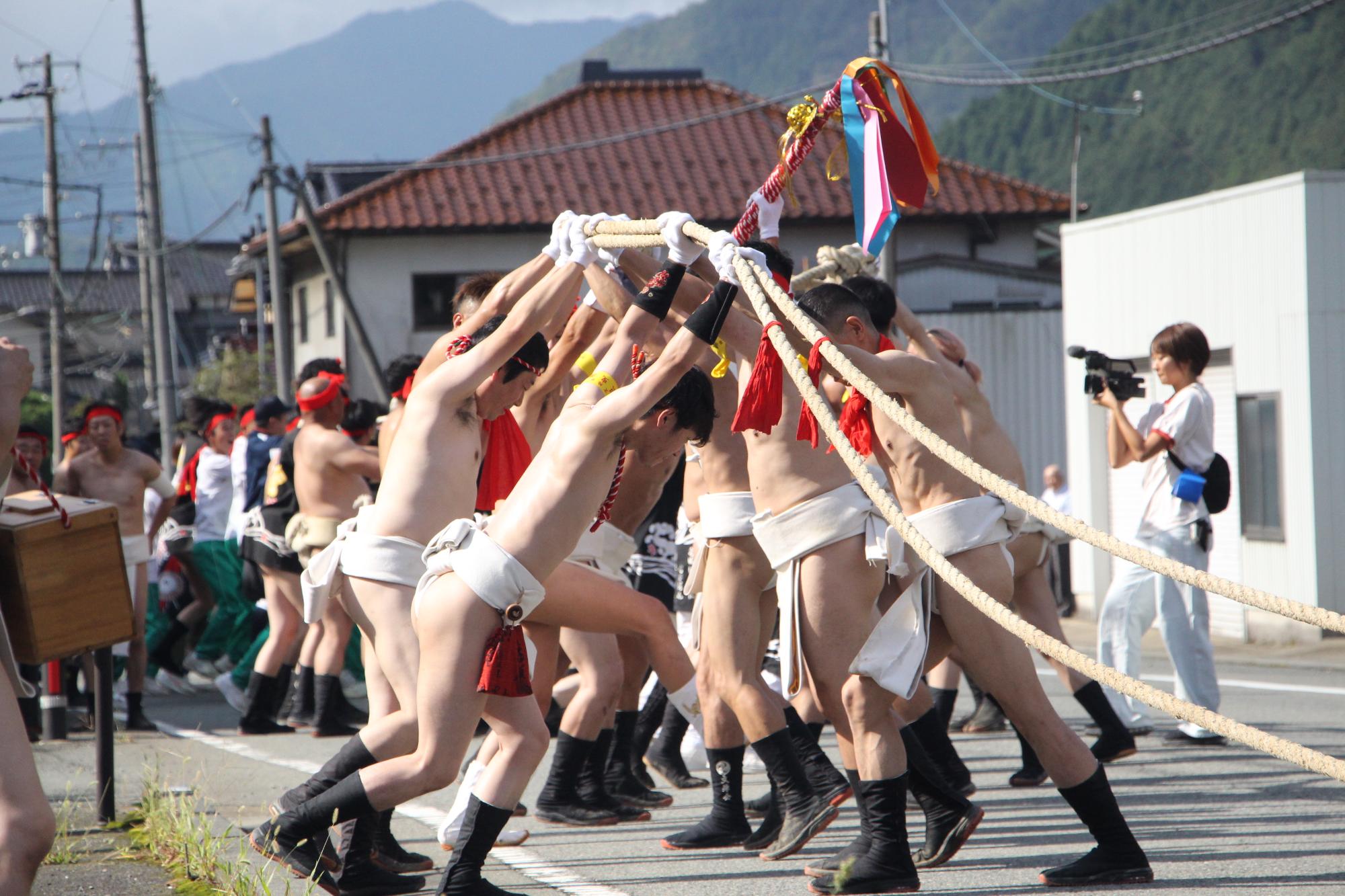 まわし姿の壇尻の引手が壇尻を引く綱を練り合わせている写真
