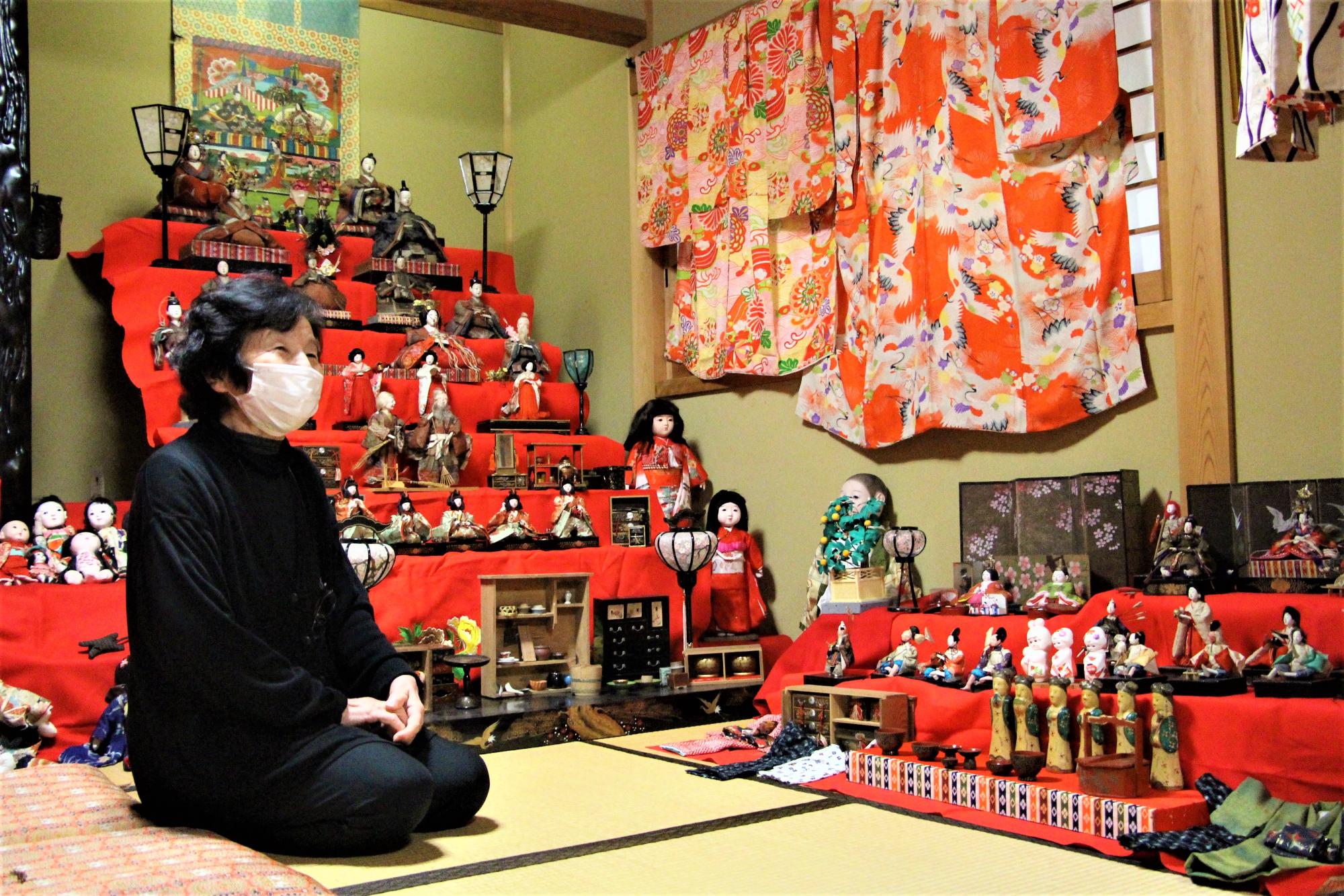 大正時代のひな壇の前で正座姿で説明をする実際寺柴山文子さんの写真