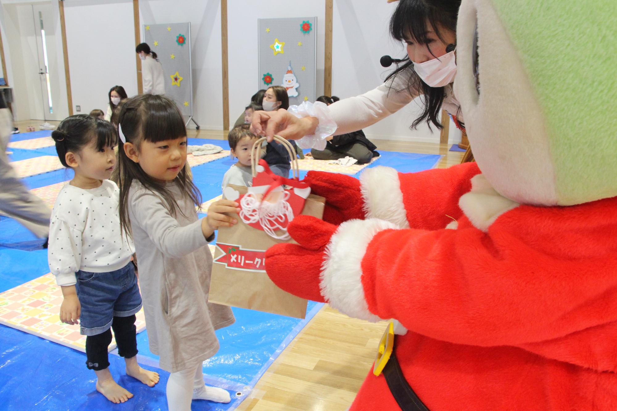 しーたんからクリスマスプレゼントを受け取る子どもの写真