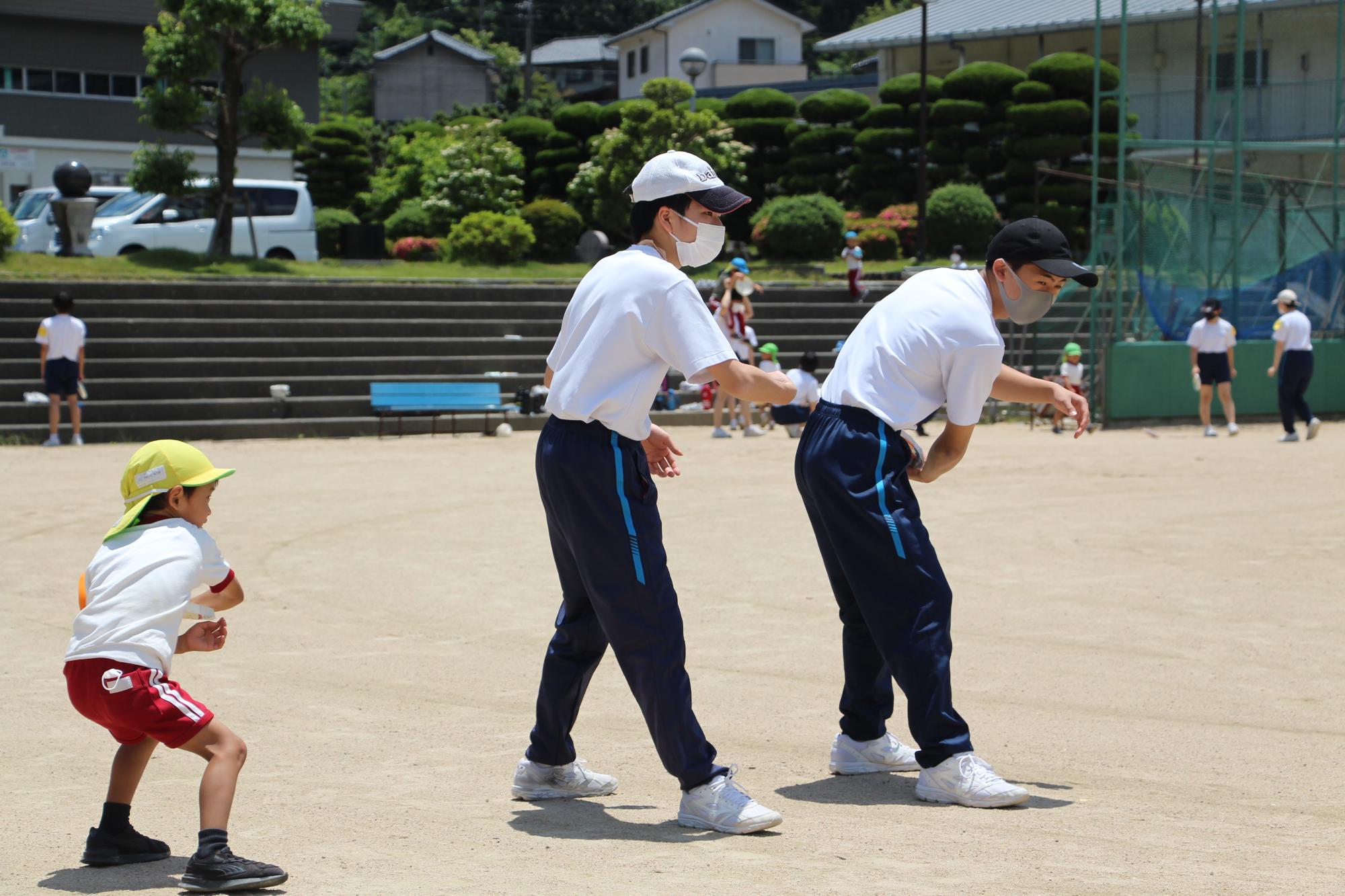 フリスビーを投げる生徒と園児の写真