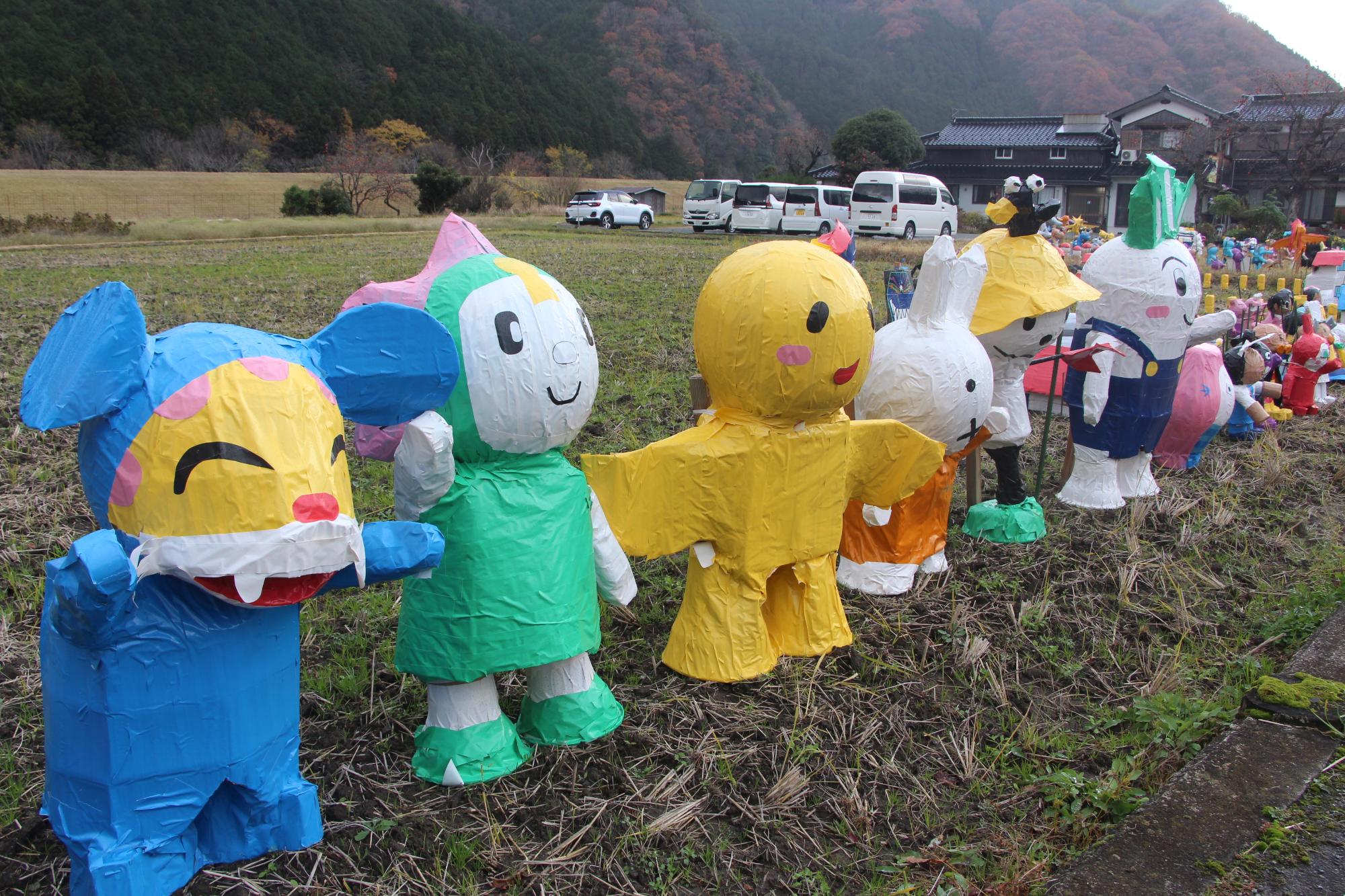 アニメのキャラクターなどをモチーフにしたかかしが田んぼのあぜに沿って並んでいる写真