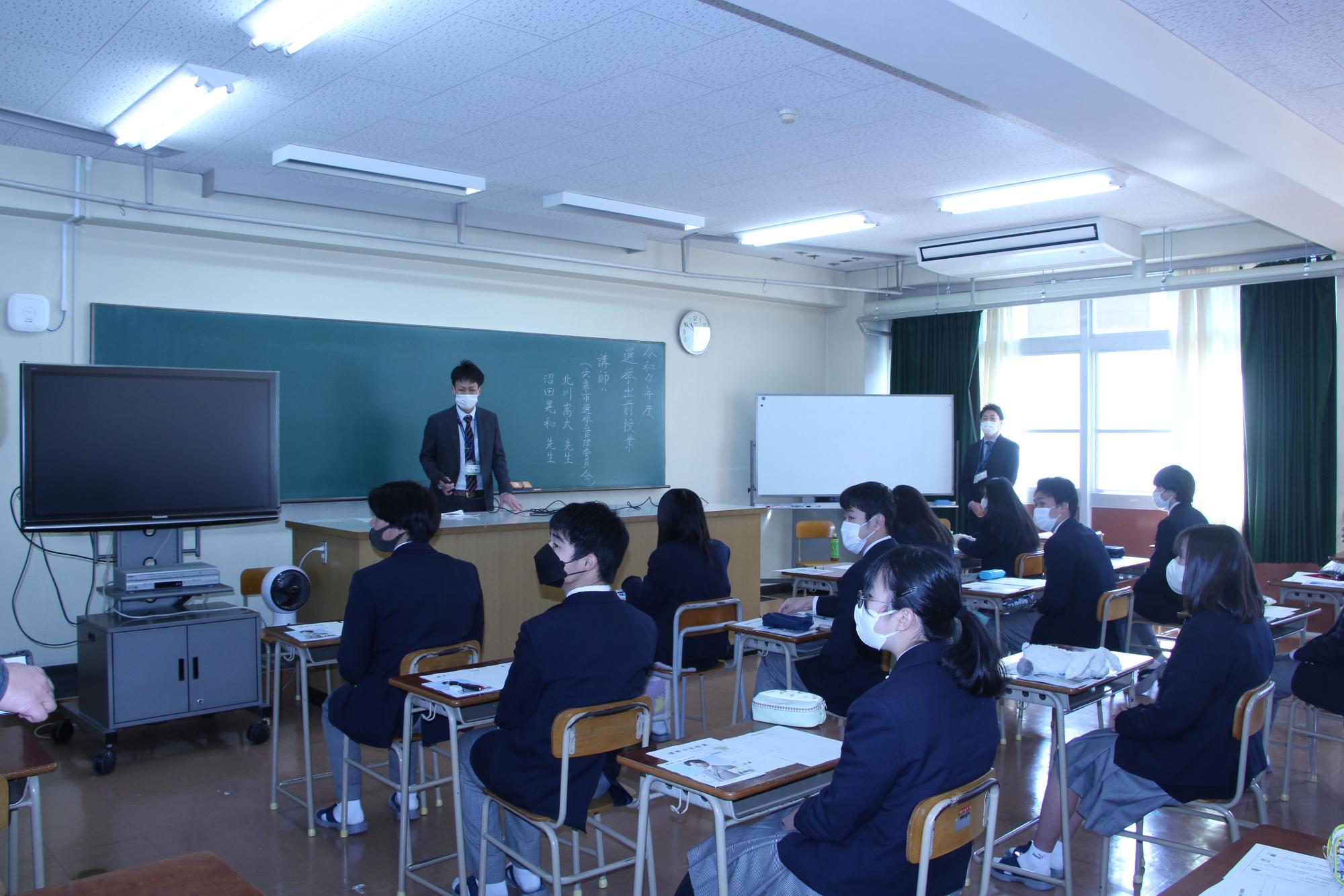 伊和高生が市の選挙管理委員会の職員から選挙の仕組みについて教室で講義を受けている写真