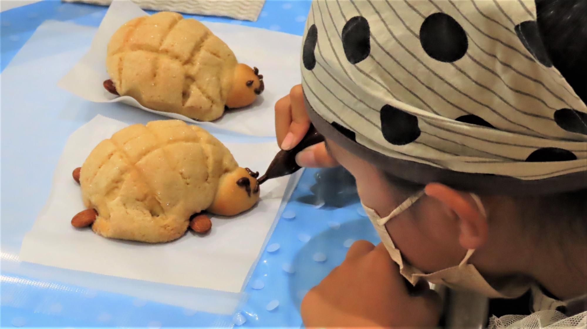 焼きあがったパンに参加者がチョコペンで顔を書いている写真