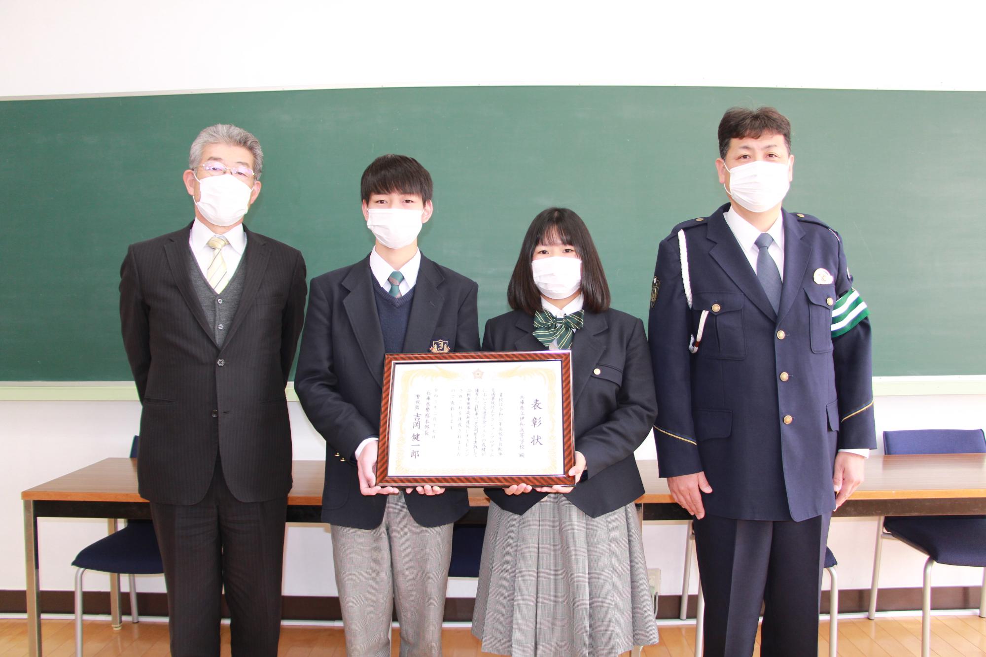 表彰状とともに伊和高等学校の生徒、校長先生、兵庫県警察の方が記念撮影をしています。