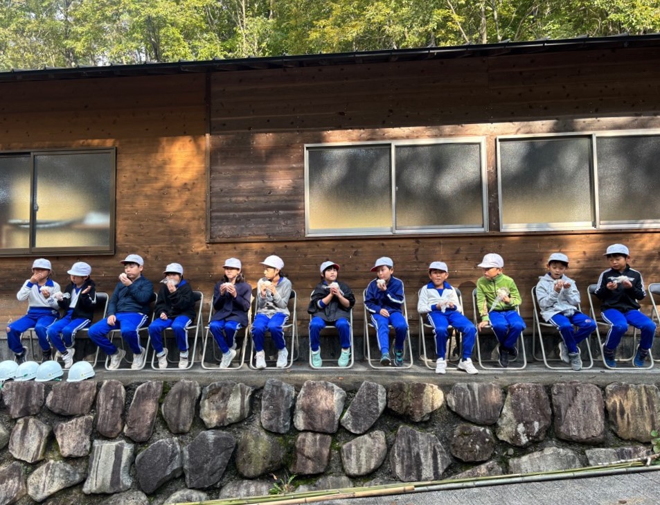 児童が自分で作ったおにぎりを一列に座って食べている様子