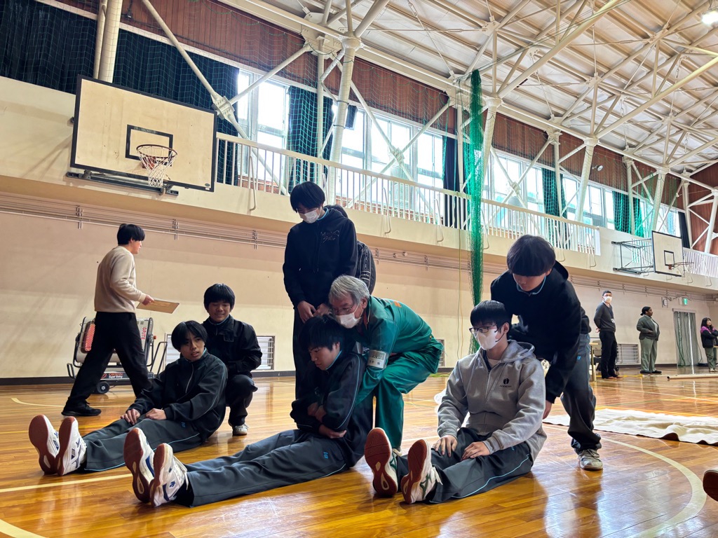 学生が傷病者を搬送する方法を防災士から学んでいる様子