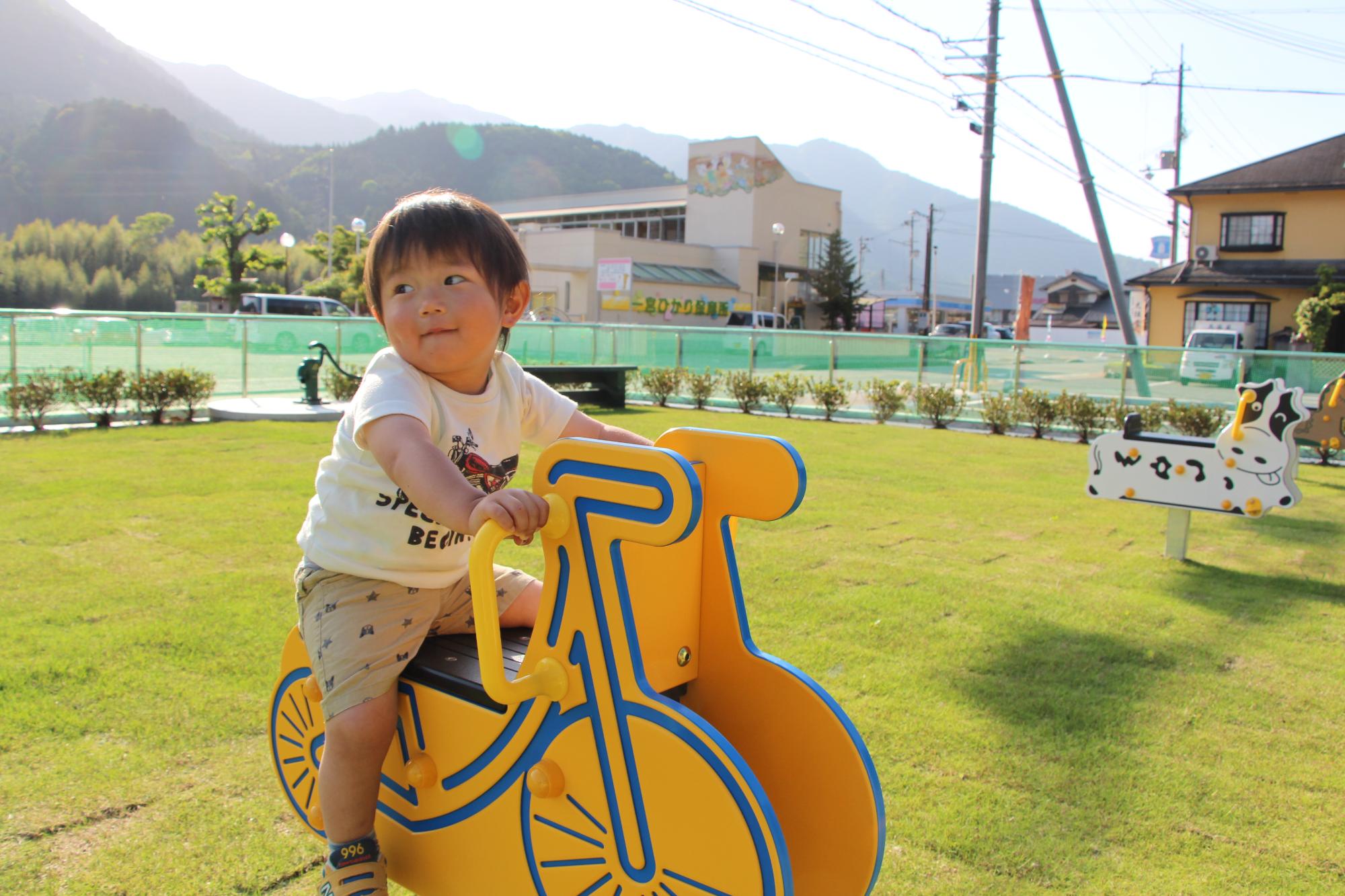 ばね仕掛けの遊具にまたがり遊んでいる子どもの写真