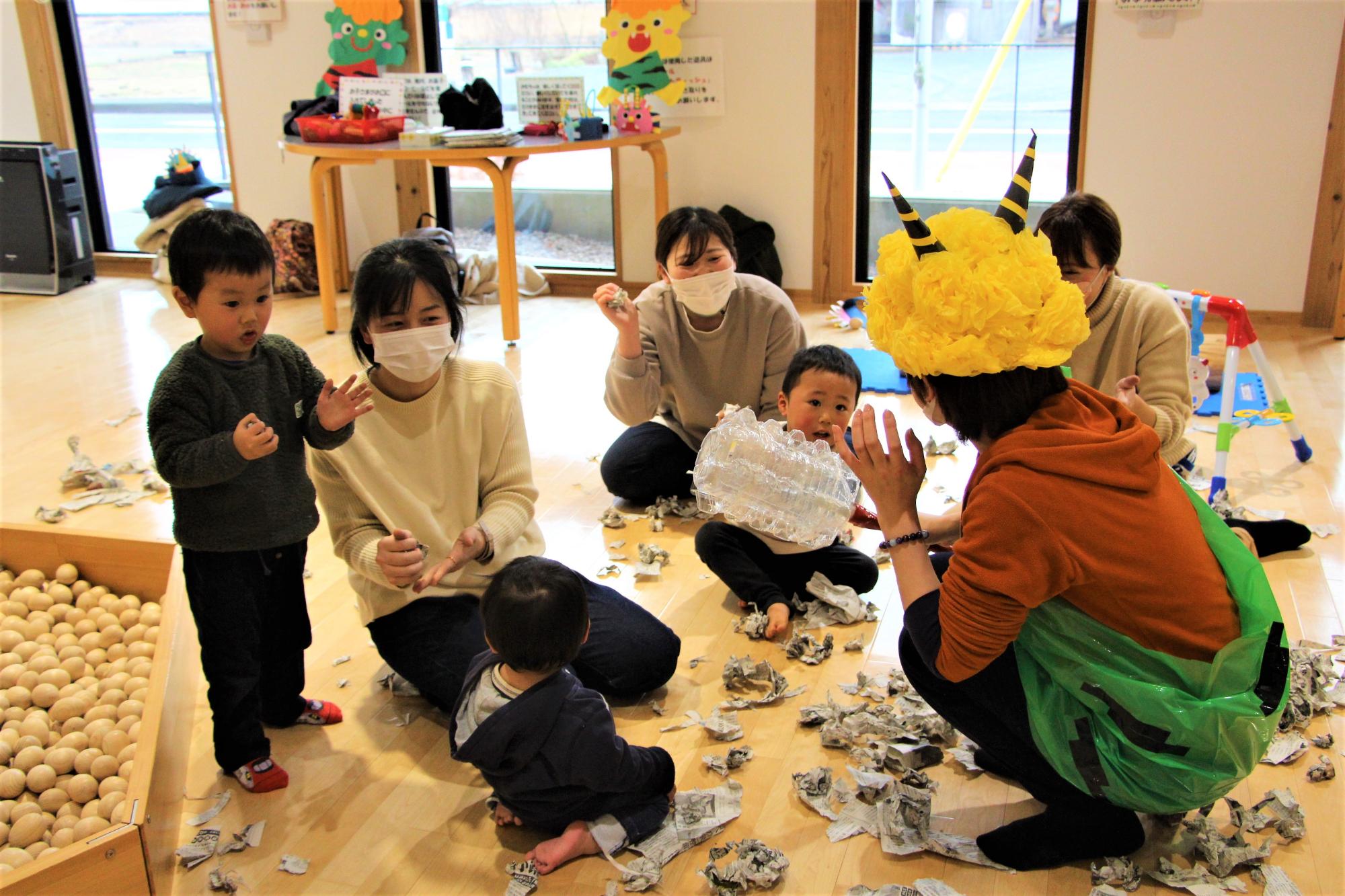 職員が扮する緑鬼が子どもたちの前にしゃがんでいる写真