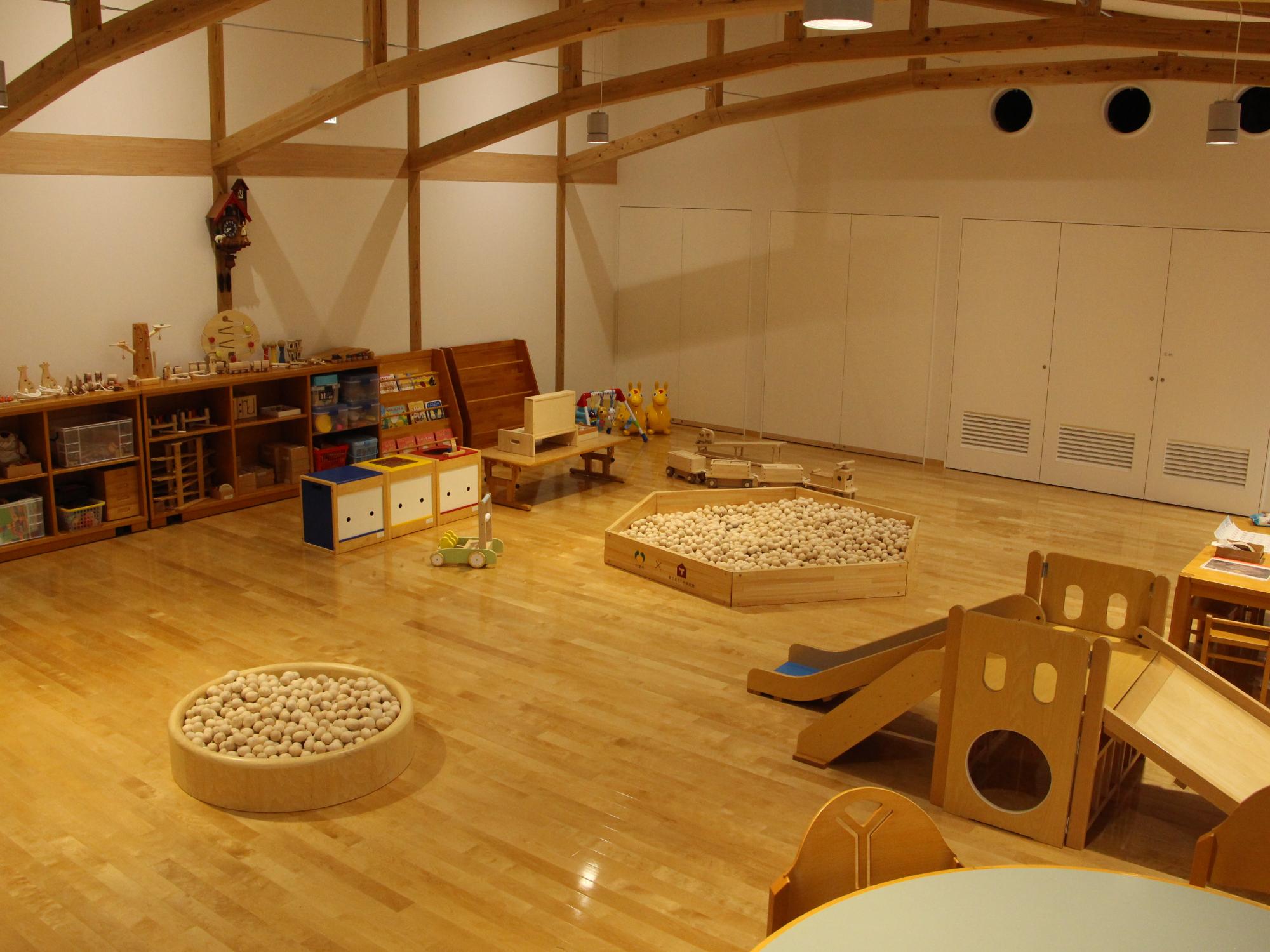 子ども向けの木のボールプールや木の滑り台が置かれたいちのぴあの遊戯室の写真