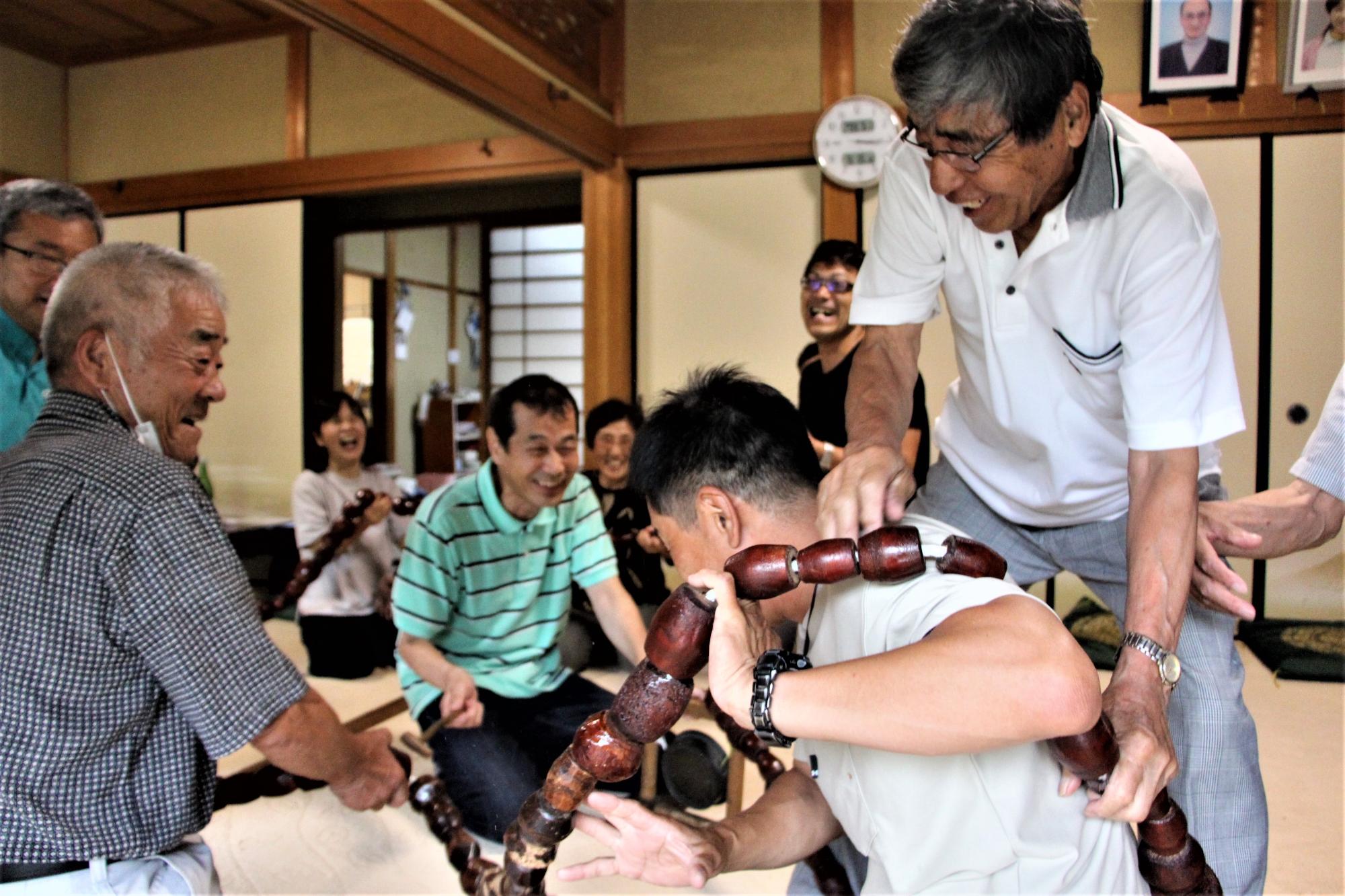数珠をまわしながら手元でたるみを作り、参加者の首や身体にかけている写真