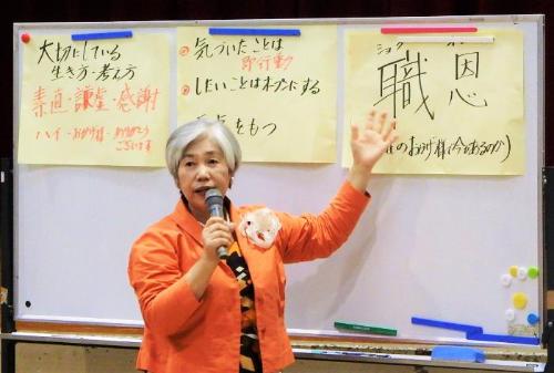 村山順子さんがホワイトボードの前に立ちマイクを持って講演の内容を説明している写真