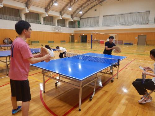 丸太卓球大会で並んだ卓球台で向かい合ってプレーをする参加者らの写真