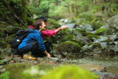 2人の女性が渓谷を流れる川の水に触れている写真