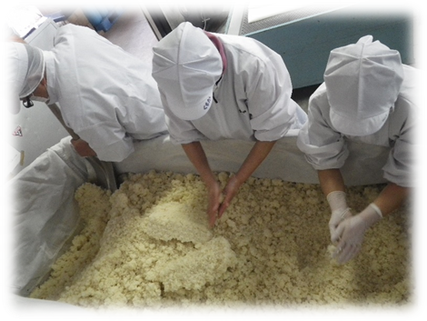 調理員3人が大量の炊いた米を攪拌している写真