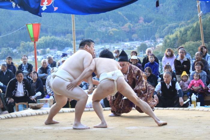 相撲を取る力士と勝敗を見守る大勢の観客の写真